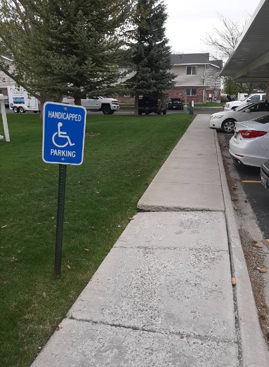 Handicap Sign By Uneven Concrete Sidewalk